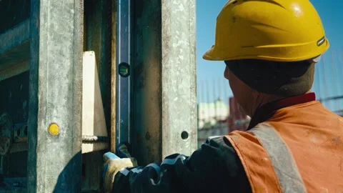 A worker checks the vertical plane with a construction level Stockbeeldmateriaal 273147808