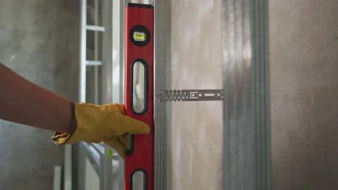 A worker checks the vertical plane with a red construction level Stock Footage 212832954