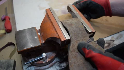 A worker clamps a part of the axe in a vise for processing. Stock Footage 156340679
