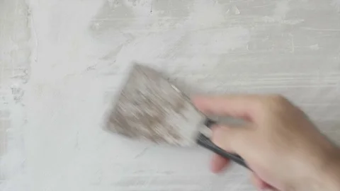 Worker Clean Old Plaster from the Wall the with a Spatula and put it on the wall Stock Footage 80482844