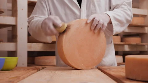 Worker cleaning and brushing the cheese wheels - traditional cheese maturation Stock Footage 154366268