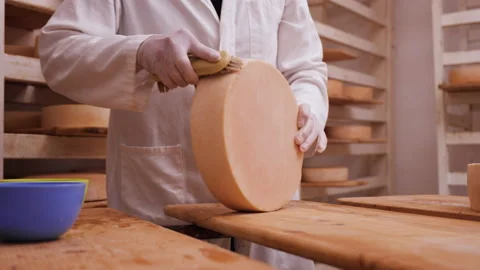 Worker cleaning and brushing the cheese wheels - traditional cheese maturation Video stock 157588927