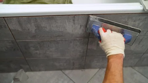 Worker Cleaning and Grouting Tile Seams Stock Photos