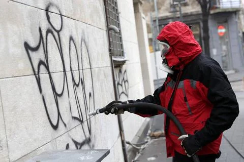 Worker cleaning graffiti Worker cleans graffiti from a public building wal... Fotos de archivo