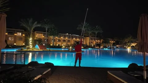 A worker is cleaning a hotel swimming pool. Stock Footage 335398896