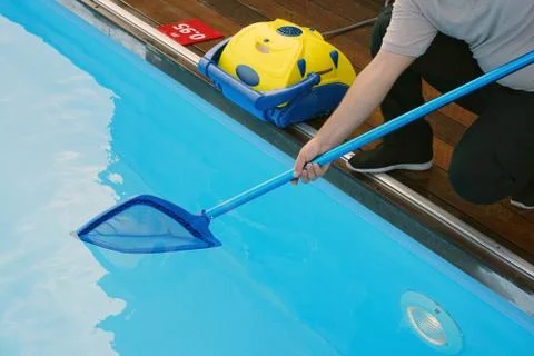 Worker cleaning the pool. Automatic pool cleaners. Stock Photos