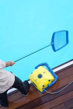 Worker cleaning the pool. Automatic pool cleaners. Stock Photos