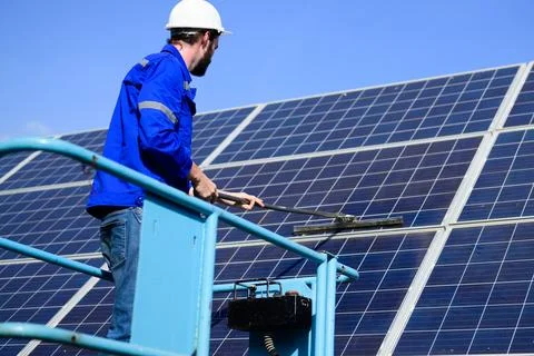 Worker cleaning solar panel at solar cell farm Stock Photos