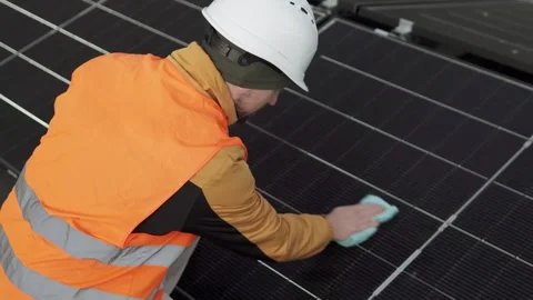 Worker cleaning solar panels, emphasizing maintenance and energy efficiency. Stock Footage 319902327