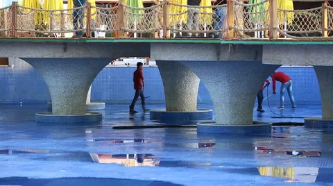 Worker is cleaning a swimming pool with a pressure pump Stock Footage 64179875