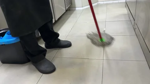 Worker cleaning tiled floor with a mop in a commercial kitchen Stock-Footage 344100317