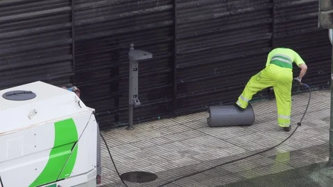 Worker cleaning a trash bin in the street with high pressure water jet Stock Footage 126824058