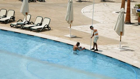 Worker is cleaning the water pool with brush Stock Footage 81813568