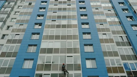 Worker cleaning windows of high rise building, dangling from secure ropes Stock Footage 138403086
