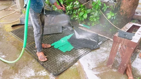 Worker cleans car rubber sheet by hose at garage Stock Footage 304851934