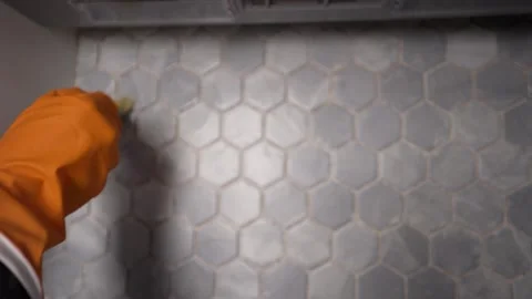 A worker cleans gray ceramic tiles and a kitchen backsplash. Stock Footage 308202648