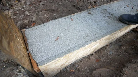 Worker cleans his shoe on a concrete foundation Stock Footage 158975752