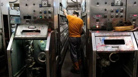 A worker cleans a machine that applies a pattern to cardboard boxes. Stock Footage 144594160