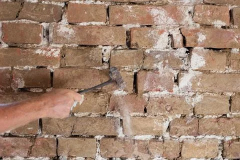 A worker cleans an old brick wall with a chisel. Renovation of an old house Foto stock
