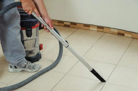 Worker cleans seams between tiles Stock Photos