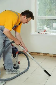 Worker cleans seams between tiles Stock Photos