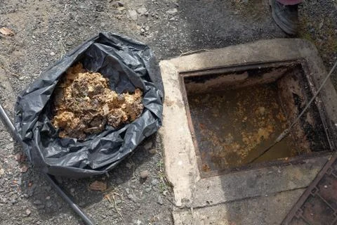 The worker clears the clogged sewer drain using drain clog remover Stock Photos