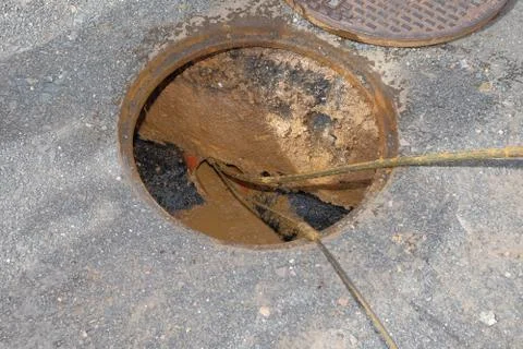 The worker clears the clogged sewer drain using drain clog remover Stock Photos