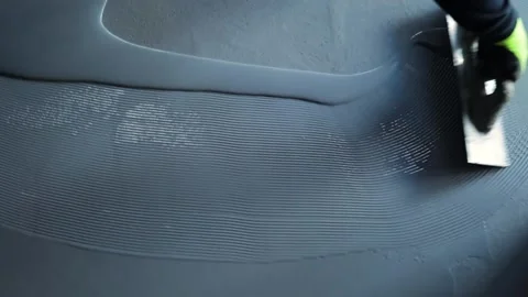 Worker, coating floor with self-leveling epoxy resin in the workshop of the p Stock Footage 150876970