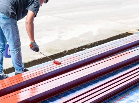 Worker coating steel post in construction site. Foto stock