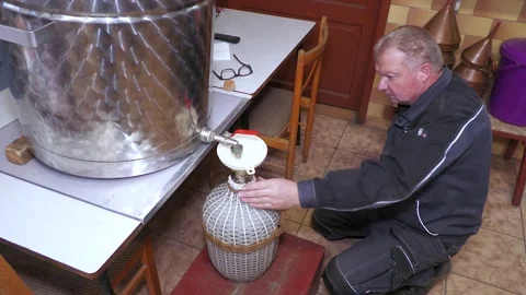 Worker Collecting Freshly Distilled Fruit Spirit in Glass Demijohn Stock-Footage 343674138