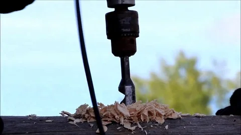 The worker collects the frame and drills a hole in a log for dowel using a drill Stock Footage 77427345