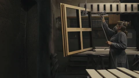 Worker is coloring the wooden window frame with black paint in the workshop room Stock Footage 164913878