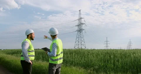Worker comes to engineer to show tablet near power lines Stock-Footage 156981822