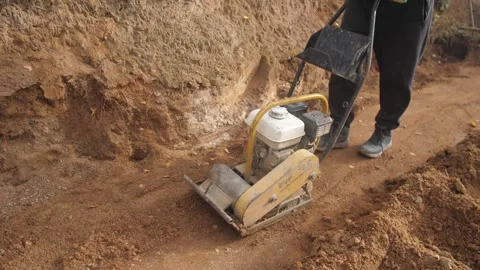 Worker compacting soil, operator uses compactor for soil, man operates plate Stock Footage 319582794