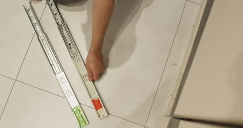 Worker compares different drawer sliding rails before installing Stock Footage 323968525