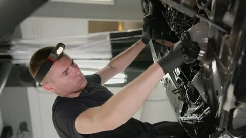 The worker concentrates on washing the car engine with a brush with soapy foam. Stock Footage 248637408
