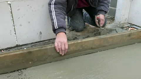 Worker concretes floor, pour cement mortar on reinforcing mesh . Stockbeeldmateriaal 223750086