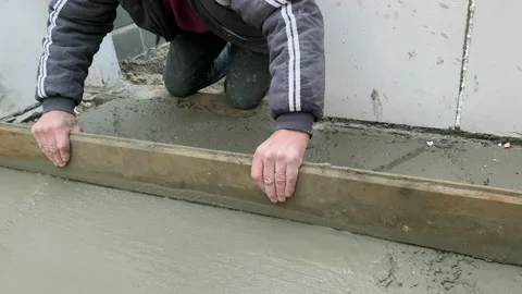 Worker concretes floor, pour cement mortar on reinforcing mesh Stock Footage 223757574