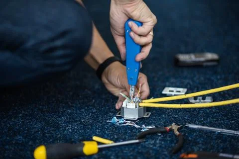 Worker connect a network cable with RJ45 sockets by punch-down tool, process of Fotos Stock