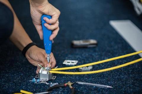 Worker connect a network cable with RJ45 sockets by punch-down tool, process  Fotos Stock
