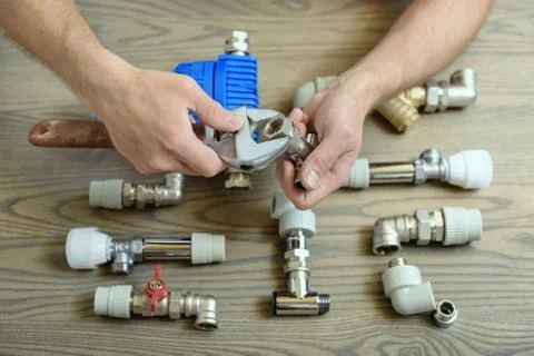 A worker is connecting elements of the plumbing. Stock Photos