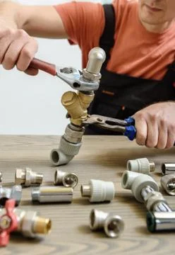 The worker is connecting elements of the plumbing. Stock Photos