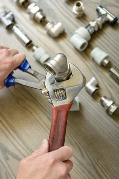 A worker is connecting elements of the plumbing. Stock Photos