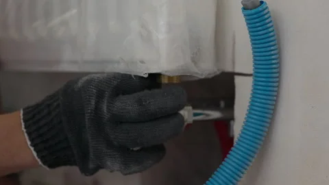 Worker connecting heating radiator during interior installation Видео 347207035