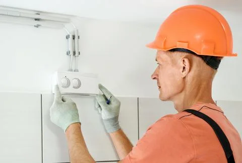 Worker is connecting the humidity sensor of the ventilation system. Stock Photos