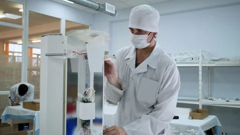 A worker is connecting the parts and assembling the medical lamp at workshop Stock Footage 190513964