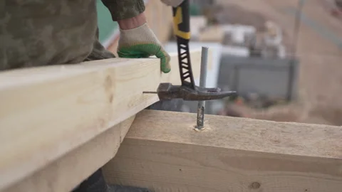Worker connects beams using long nails and heavy hammer Stock Footage 311892811