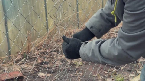 The worker connects the metal mesh to each other. Сhain-link fence. Stock Footage 157286922