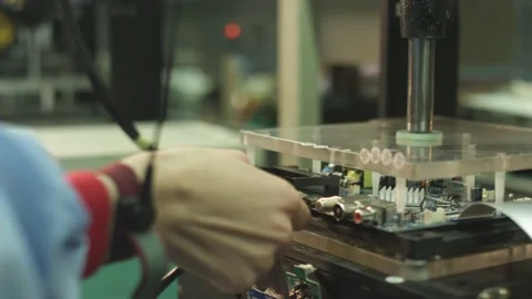Worker connects wires to an electronic board and checks it in a TV factory Stock Footage 162364972
