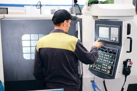 A worker at the console of a high-tech machine adjusts the parameters Stock Photos